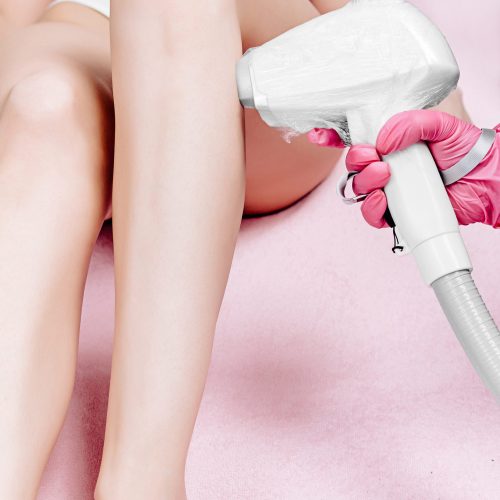 A young beautiful woman is sitting on a pink couch, Undergoing a laser hair removal procedure on her legs in the calf area. Professional body care service in a beauty salon